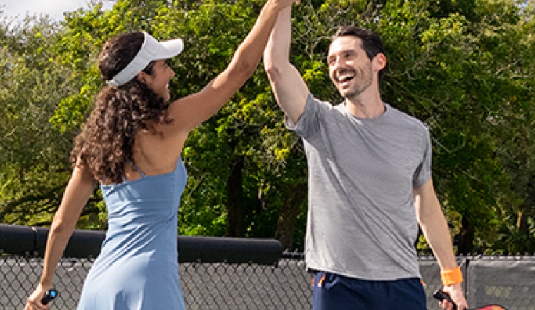 Two people high fiving while playing pickleball